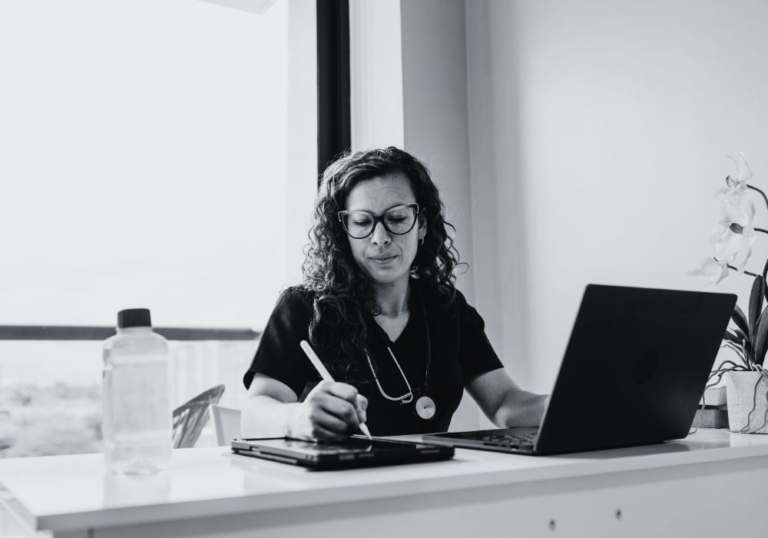 Healthcare professional working on a laptop at a medical office