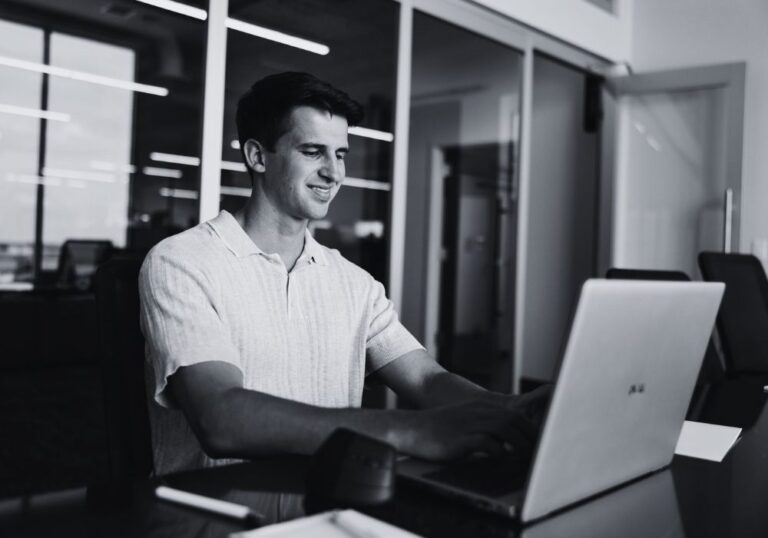 Business professional using a laptop in a modern office environment.