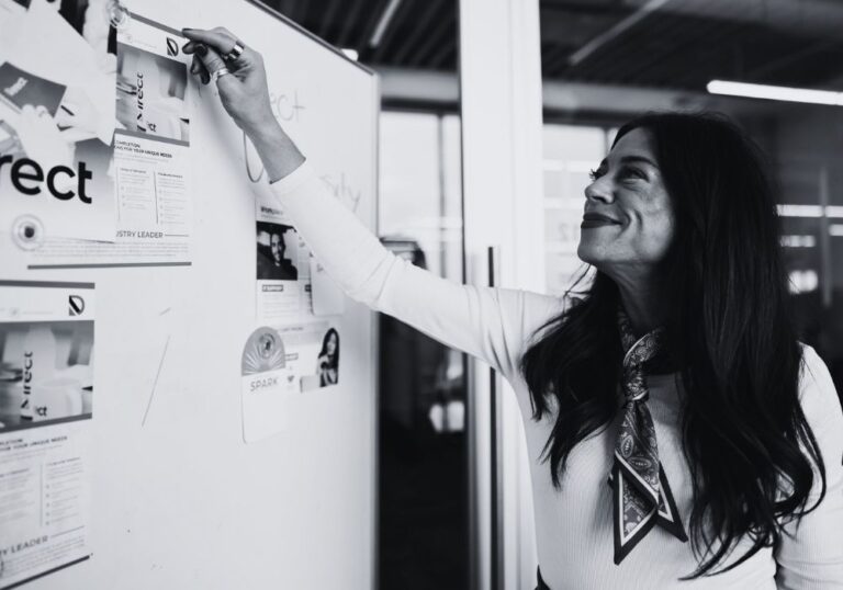 Team member reviewing ideas and documents on a whiteboard during a collaborative planning session.