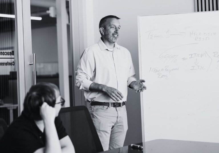 Team member presenting ideas at a whiteboard during a business planning meeting.