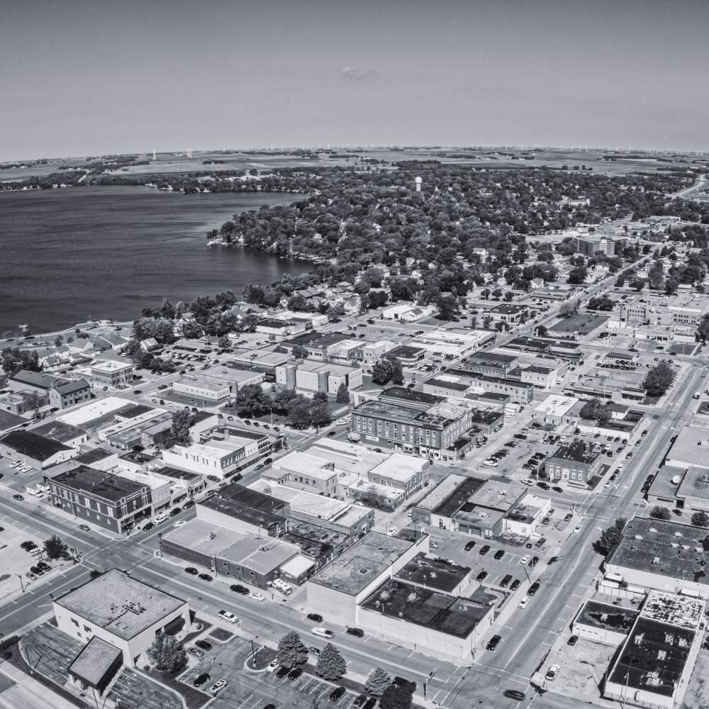 Black-and-white aerial view of a downtown business district with buildings, streets, and a nearby lake