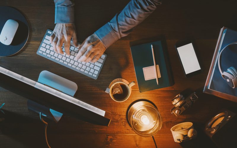Businessman sitting at office desk and working with his computer, top view