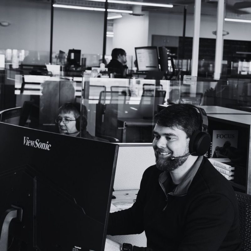 Workplace IT technician providing remote support from a help desk workstation.