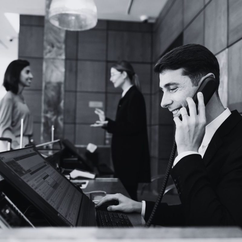 Hotel front desk employee assisting a guest during check-in at a hospitality property.